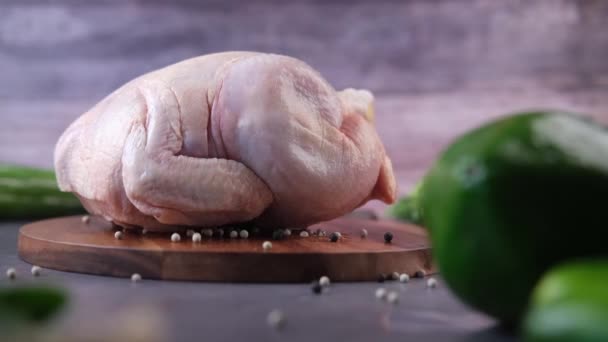Целый сырой цыпленок на доске со свежими овощами — стоковое видео