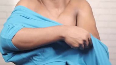 Genç adam gömleğini giydi.,