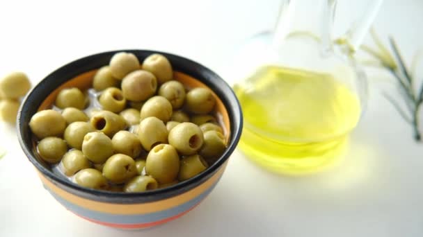 Sticlă de ulei de măsline și măsline proaspete într-un recipient pe masă  . — Videoclip de stoc