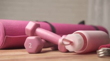  Pembe halterler, spor paspası ve beyaz arka planda su şişesi. 