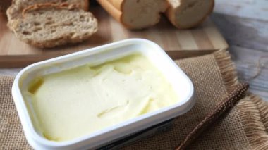 Kesme tahtasında tereyağı kesme ve arka planda kahverengi ekmek 
