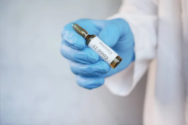 Mano en guantes de látex que contienen la vacuna de ampolla de vidrio, con espacio para copiar — Foto de Stock