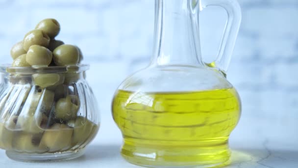 Botella de aceite de oliva y aceituna fresca en un recipiente sobre la mesa . — Vídeo de stock