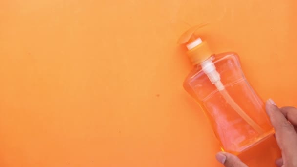 El yıkama sıvısı kabı ve yüz maskesini turuncu arka plana koy — Stok video