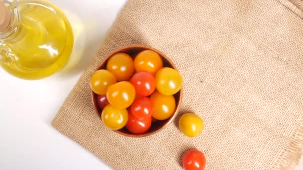 Tomate cherry colorido en un tazón y aceite de oliva en la mesa — Vídeo de stock