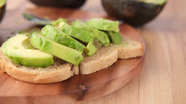 Plak avocado op bruin brood op tafel — Stockvideo