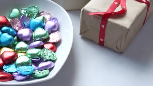 Kleines herzförmiges Geschenk mit Süßigkeiten auf weißem Hintergrund — Stockvideo