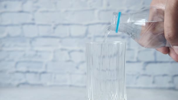 Versando acqua in un bicchiere da un contenitore di plastica sul tavolo — Video Stock