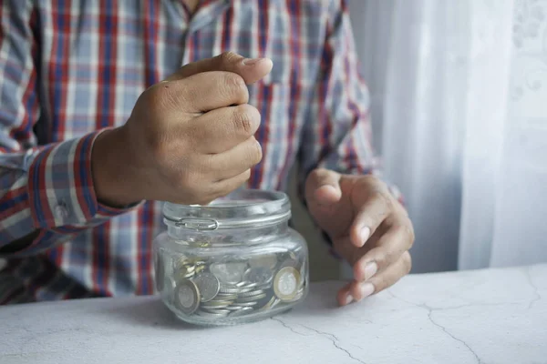 Young man saving coins in a jar white sited — Stock Photo, Image