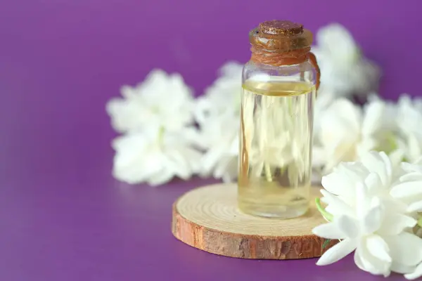 Aceites esenciales de eucalipto en una botella de vidrio y flor sobre fondo púrpura — Foto de Stock