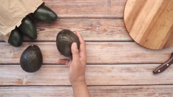 Πάνω όψη του χεριού πάρει φέτα αβοκάντο σε ξύλινο τραπέζι — Αρχείο Βίντεο