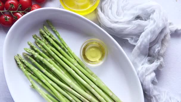 Espárragos verdes y aceite de oliva en un tazón en la mesa — Vídeo de stock