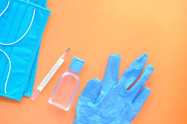 Surgical masks, medical gloves and hand sanitizer on orange background — Stok fotoğraf