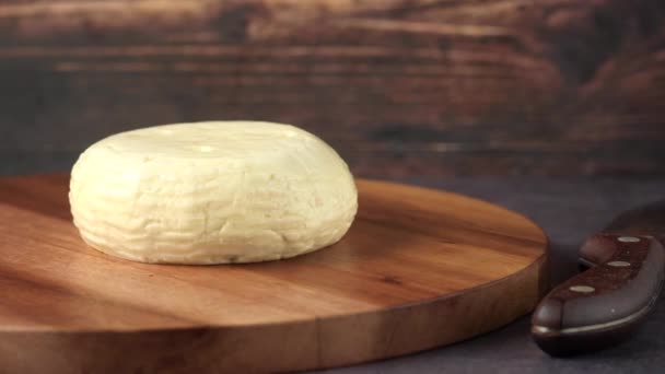 Round shape cheese on chopping board on table — Αρχείο Βίντεο