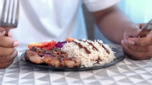 Молодий чоловік чекає на їжу курки на грилі, рису та салату на тарілці на столі — стокове відео