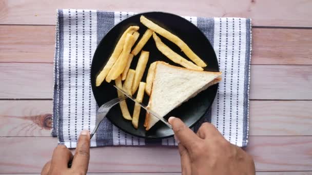 Mans hand eten kip sandwich en chips op bord, bovenaanzicht — Stockvideo