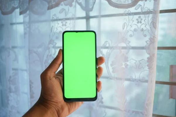 Nahaufnahme der Hand eines jungen Mannes mit Smartphone mit grünem Bildschirm — Stockfoto