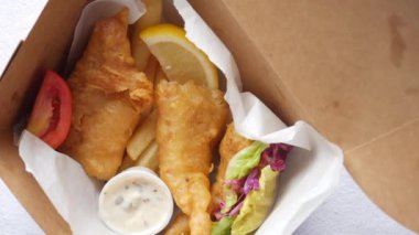 Balık fileto, limon, paket servis kutusunda cips.