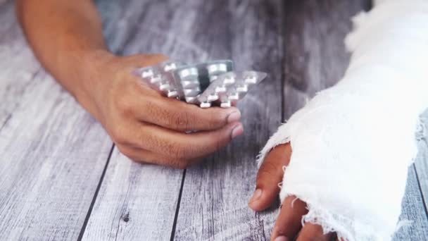 Poraněná bolestivá ruka s obvazem a s pilulkami v blistru — Stock video