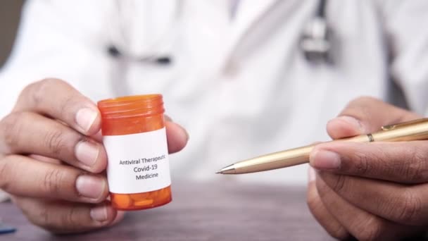Arzt Hand hält covid 19 medizinische Pillen Behälter und zeigt mit Stift — Stockvideo