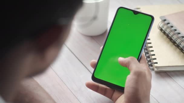 Vista trasera de la mano del hombre joven utilizando el teléfono inteligente con pantalla verde — Vídeos de Stock