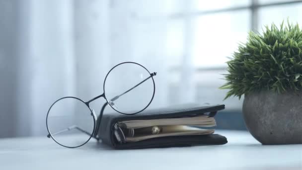 Bloc de notas, anteojos y un lápiz sobre una mesa de madera — Vídeo de stock