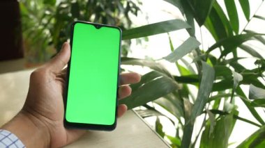 Yeşil ekranlı akıllı telefon kullanarak genç adamın elini kapat. 
