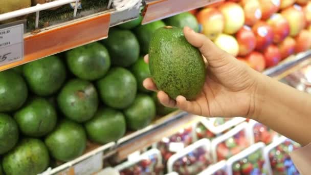 Jonge vrouwen hand houden avocado winkelen in de winkel — Stockvideo