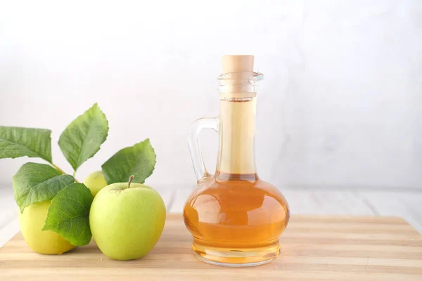 Cuka apel dalam botol kaca dengan apel hijau segar di atas meja — Stok Foto