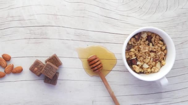 Cereálie snídaně v misce, med, čokoláda a mandlové oříšky na stole — Stock video