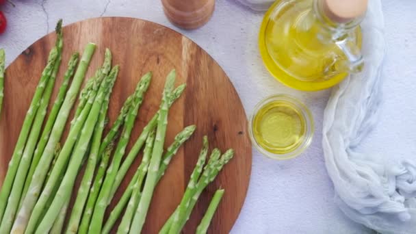 Espárragos verdes, aceite de oliva y tomate cherry en la mesa — Vídeo de stock