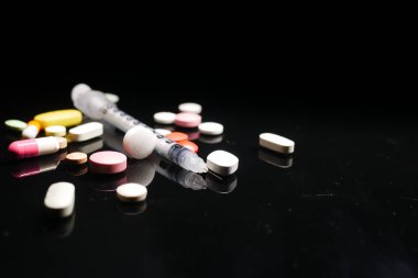 Karanlık arka planda şırınga ve haplar, kapatın. 