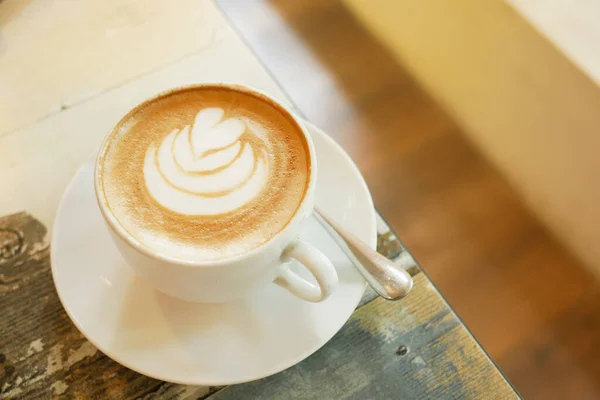 Uma xícara de café tarde com design de forma de flor no topo no café — Fotografia de Stock