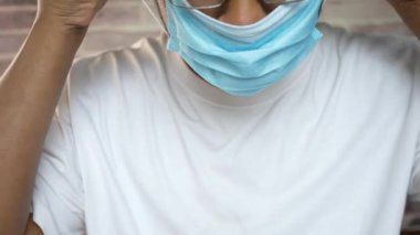 Genç Asyalı adam cerrahi yüz maskesi takıyor. 