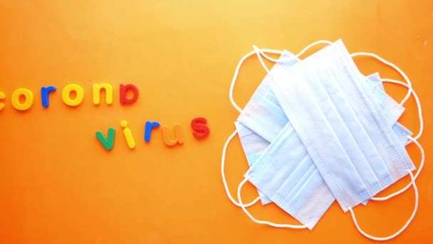 Primer plano de máscaras quirúrgicas azules y colorido alfabeto plástico en naranja — Vídeo de stock