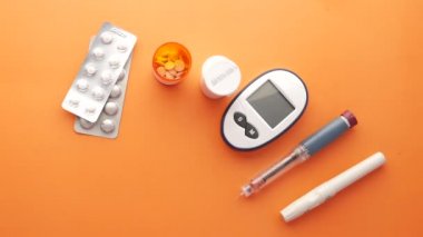 insülin kalem, diyabetik ölçüm araçları ve turuncu arka planda haplar 