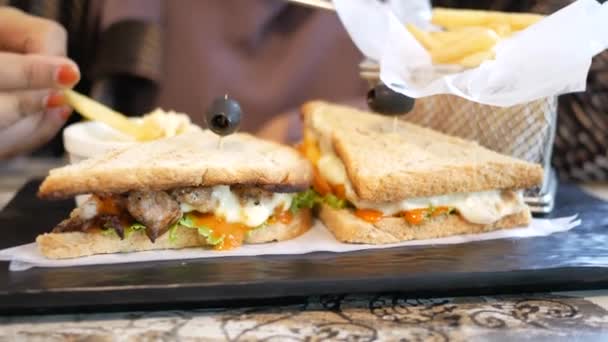 Сэндвич с курицей и чипсы на тарелке за столом кафе — стоковое видео
