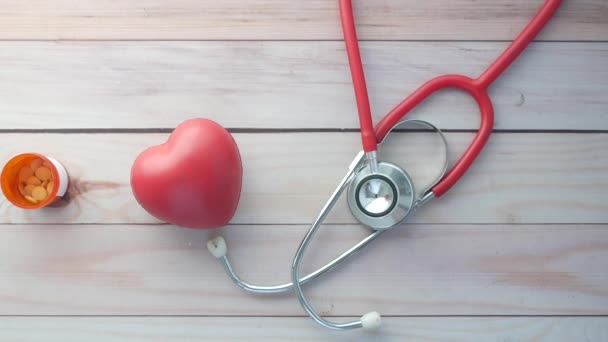 Heart shape symbol and stethoscope on wooden background — Stock Video