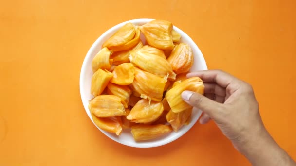 Ručně vybrat plátek jackfruits v misce na oranžovém pozadí . — Stock video