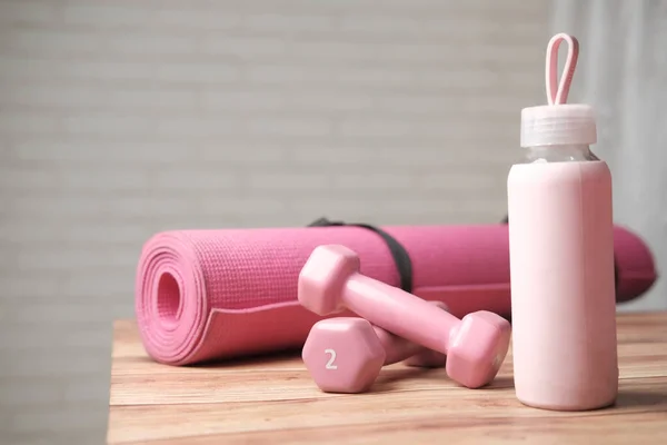 Mancuerna de color rosa, esterilla de ejercicio y botella de agua sobre fondo blanco — Foto de Stock