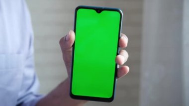 Yeşil ekranlı akıllı telefon kullanarak genç adamın elini kapat. 