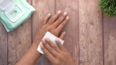 Genç adam ıslak mendille masayı temizliyor. 