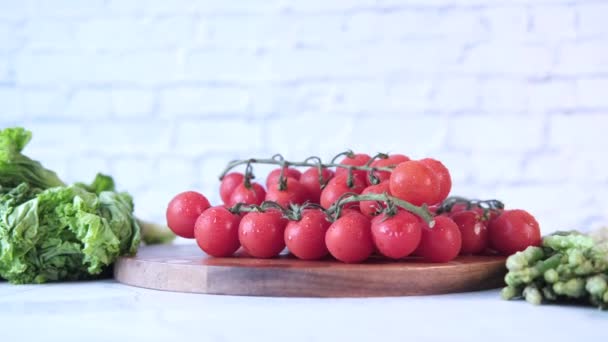 Tomate cereza de color rojo en una tabla de cortar en la mesa con espacio para copiar — Vídeo de stock