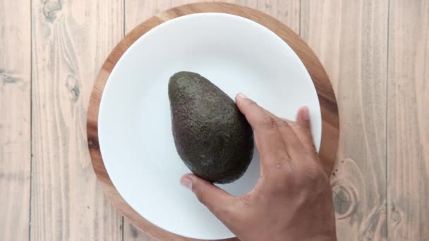 Bovenste aanzicht van plak avocado op een bord op houten tafel — Stockvideo