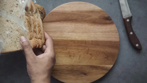 Bir dilim kahverengi ekmeği doğrama tahtasına koymak — Stok video