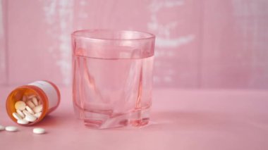  Pembe üzerine beyaz renkli tıbbi haplar dökülüyor. 