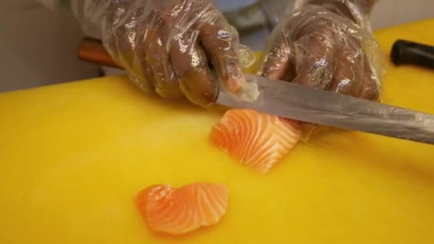 Chief cutting raw salmon fillets on a yellow table — Vídeos de Stock