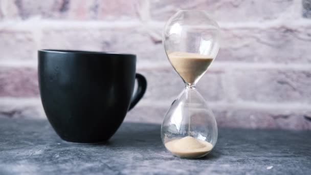 Sablier sur la table, sable coulant à travers l'ampoule de verre de sable — Video