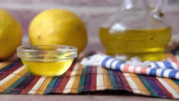 Recipiente de vidrio de aceite y limón en la mesa — Vídeos de Stock