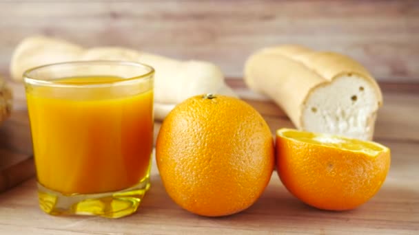 Стакан апельсинового сока и хлеб из цельного зерна на столе — стоковое видео